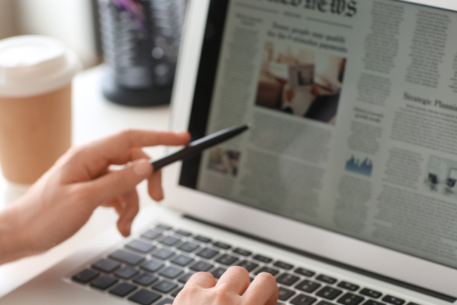 image of a person reading an online newspaper on their laptop