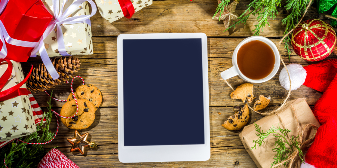 A photo of a tablet surrounded by holiday presents and decorations.